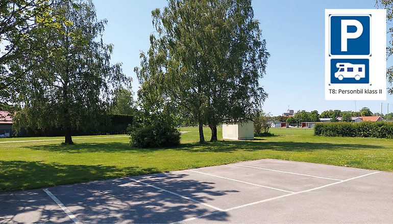 Bild på en asfaltsplan med vita rutor. I hörnet finns en parkeringsskylt och en husbilsskylt